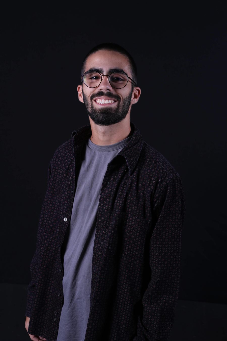 Jorge Franco, psicólogo, sorrindo, de óculos redondos e camisa escura